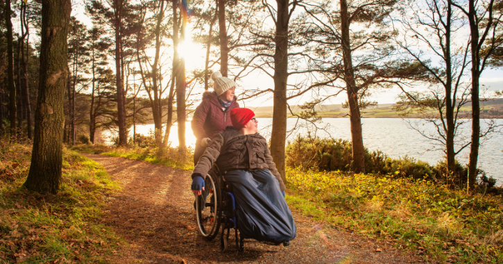 Mother and son in wheelchair walking along path as sun rises at Derwent Waterside Park.